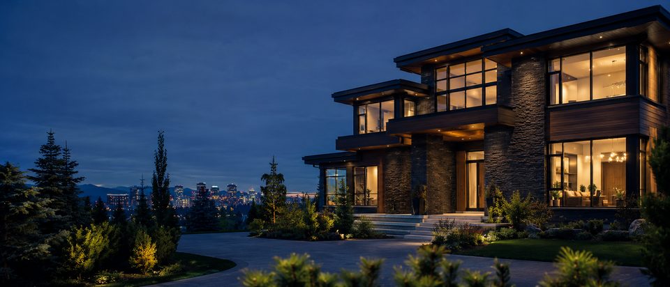 A contemporary home lit from within at dusk on a Calgary-area street, with the city skyline glowing in the distance.